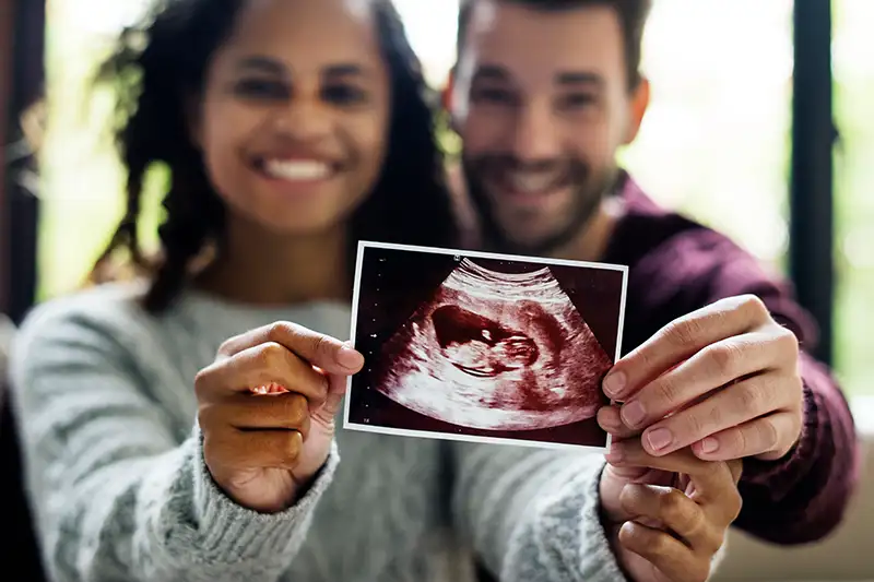 Intended parents holding sonogram and starting a family with LifeBridge Surrogacy in California