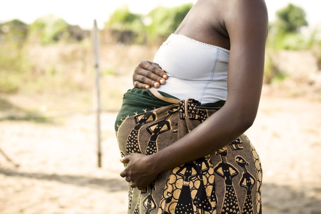 A pregnant African woman holding her stomach.
